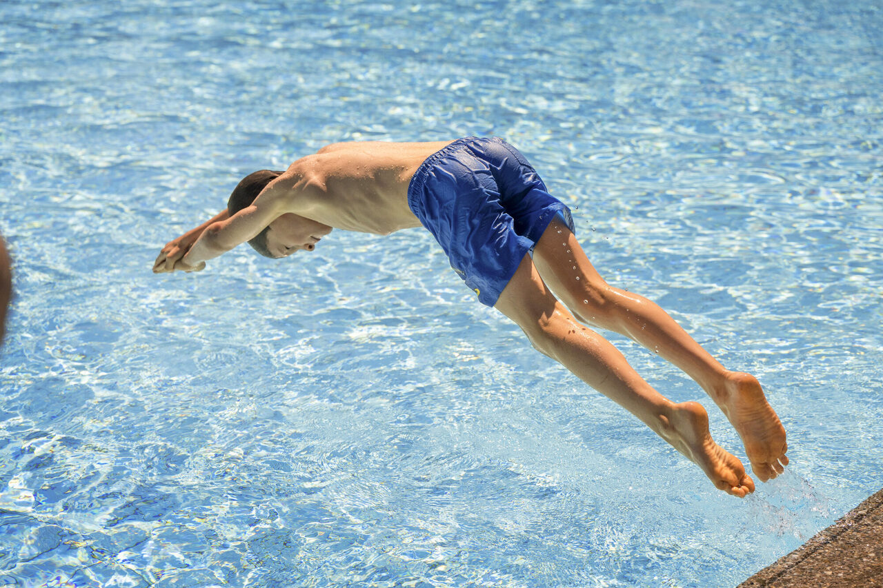 Kind springt kopfüber ins kühle Nass