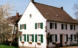 historisches weißes Lehrerhaus mit grünen Fensterläden