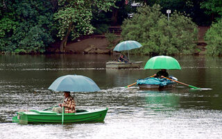 Angler bei Regen mit Schirmen auf Booten