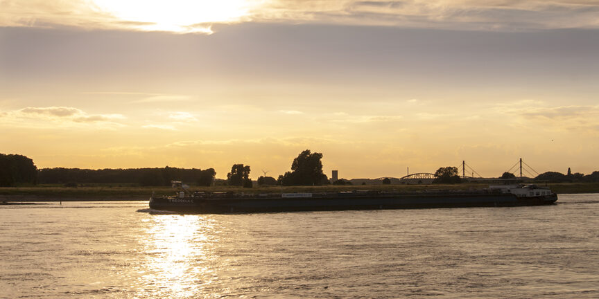 Containerschiff auf dem Rhein bei Sonnenuntergang